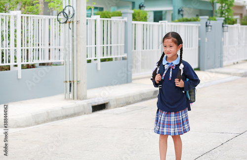 Portrait of happy asian little kid girl in school uniform walking on street leave home to go to school at morning