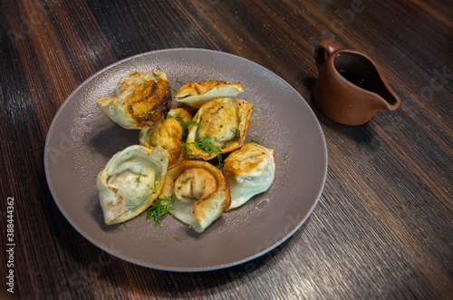 Fried Dumplings stuffed with meat, sprinkled with chopped dill, served with soy sauce