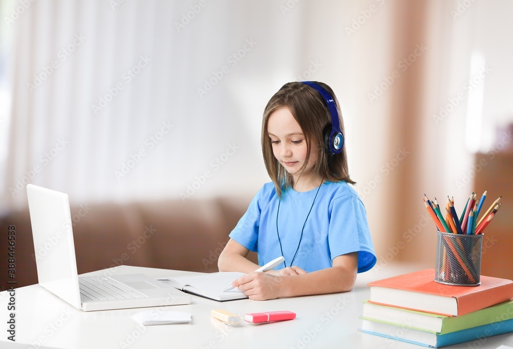 Little girl learning for school desk with headphones Little girl learning for school desk with headphones