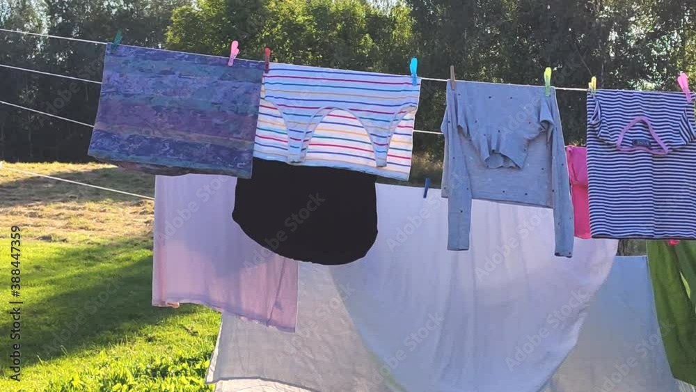 Colorful cotton laundry hanging on the rope outdoors. The process of air drying clothes