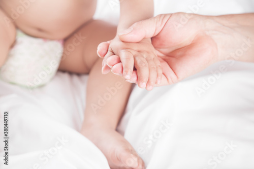 Grandmother holds the little baby hand in bed.