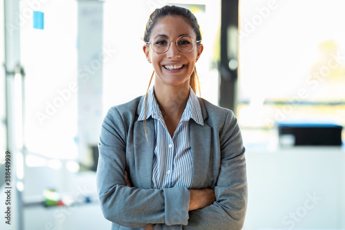 Smiling young businesswoman looking at camera while standing in the office.