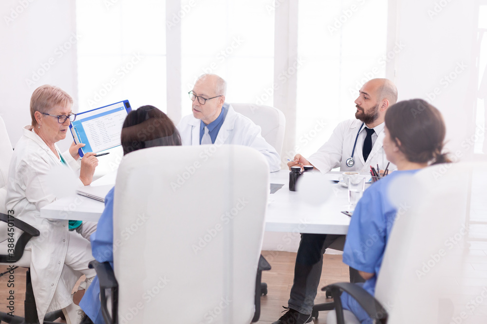 Medical staff gathered in conference room talking about patient disease. Clinic expert therapist talking with colleagues about treatment , medicine professional Medical staff gathered in conference room talking about patient disease. Clinic expert therapist talking with colleagues about treatment , medicine professional