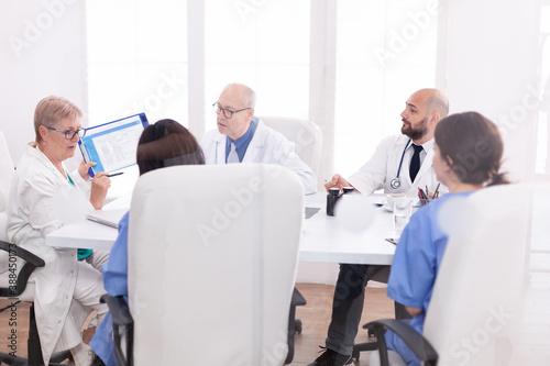 Medical staff gathered in conference room talking about patient disease. Clinic expert therapist talking with colleagues about treatment , medicine professional