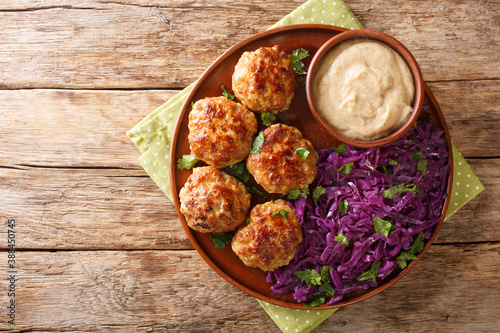 Frikadeller or Danish Meatballs are savory meatballs served with rich creamy sauce and stew red cabbage close up in the plate on the table. horizontal top view from above photo