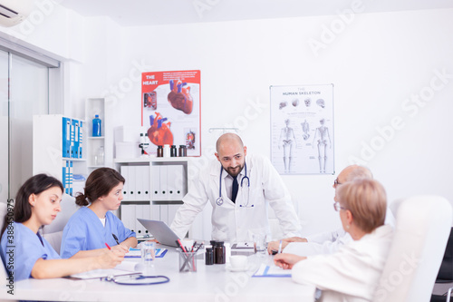 Doctor having professional discussion with medical staff in hospital meeting room. Clinic expert therapist talking with colleagues about disease, medicine professional