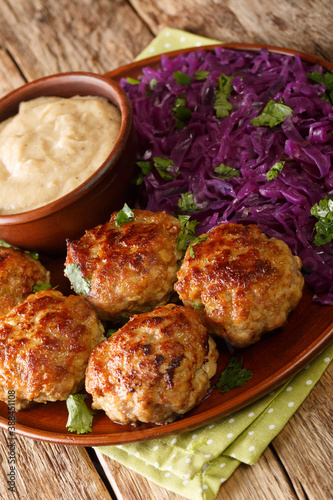 Danish meatballs frikadeller served with stewed red cabbage garnish close-up in a plate on the table. vertical photo