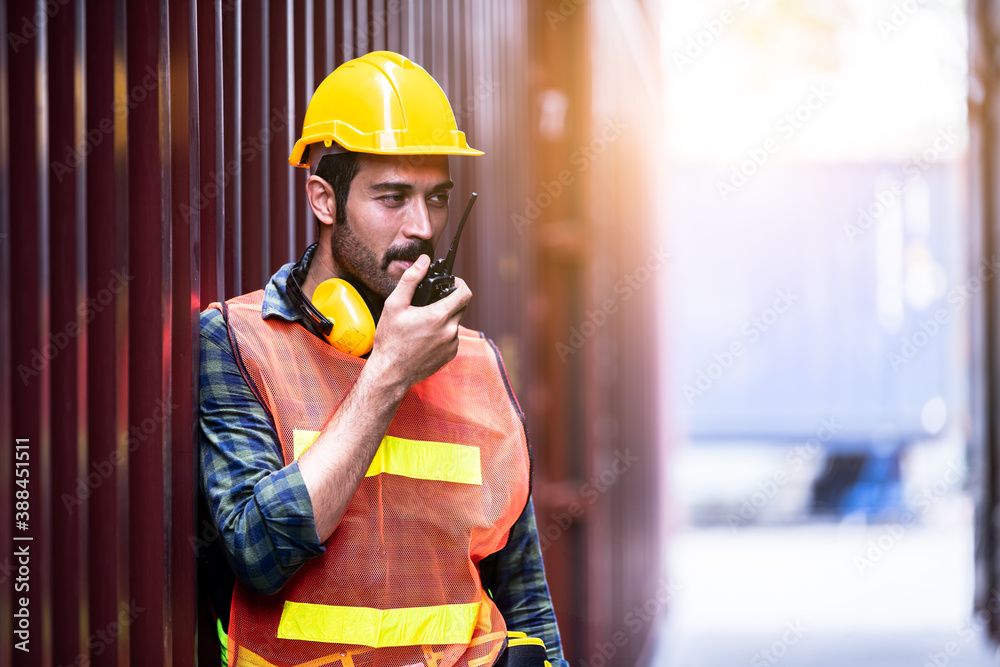 Dock worker under discussion about dock container shipping warehouse working, he wearing safety uniform hard hat ,earphone and hold radio communication. Dock worker under discussion about dock container shipping warehouse working, he wearing safety uniform hard hat ,earphone and hold radio communication.