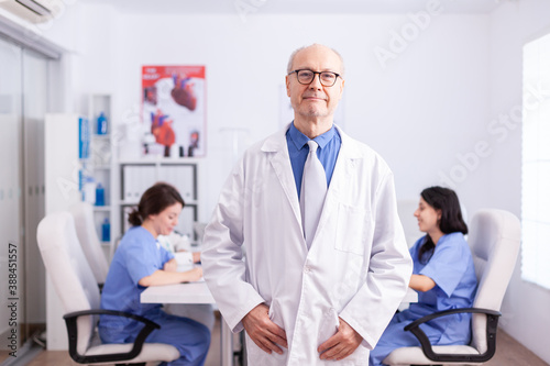 Elderly aged expert doctor in hospital conference room wearing lab coat.