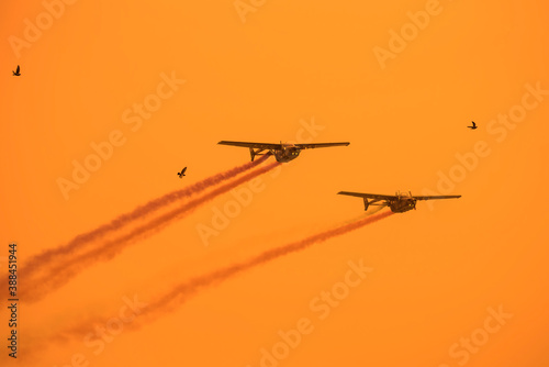Silhouette soldier has drive plane to training and show on sky with colorful smoke ,silhouette flock of birds soft sun sky background