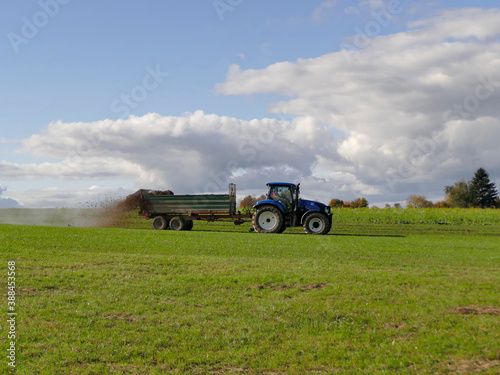 tractor throwing cow manure on a meadow in autumn in Germany