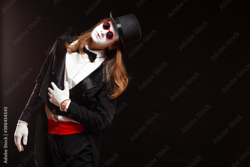 Portrait of male mime artist performing, isolated on black background. Man is standing straight tilt his head with his hand on the stomach Portrait of male mime artist performing, isolated on black background. Man is standing straight tilt his head with his hand on the stomach