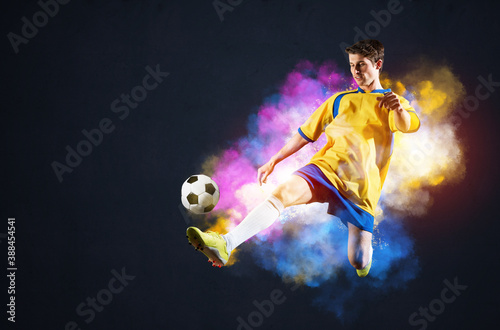 Soccer player kicking ball in colorful smoke