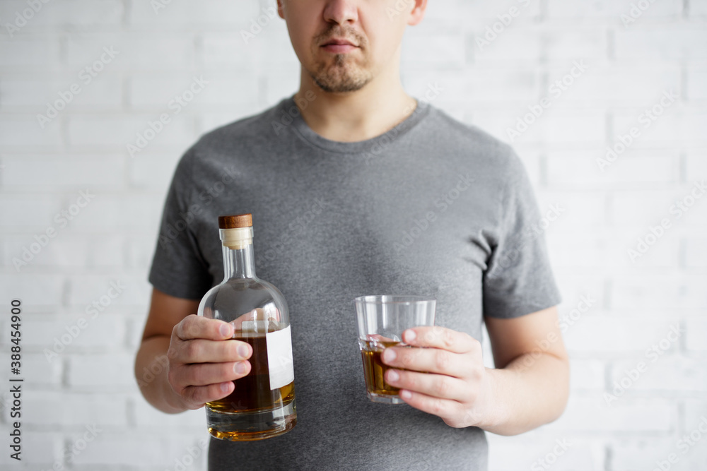 alcoholism concept - glass and bottle of whiskey in male hands alcoholism concept - glass and bottle of whiskey in male hands