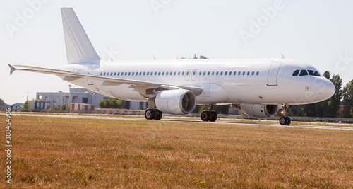 A white plane on the airport runway is taxiing. Takeoff and landing. Arrival and departure. Place for text. Passenger plane isolated mockup. Airplane landing. Travel by air transport. Copy space.