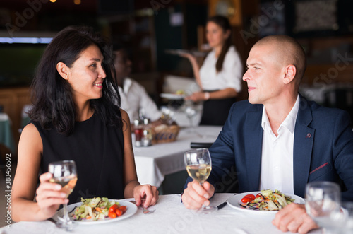 Happy elegant couple enjoying dinner with wine on romantic date in cozy restaurant © JackF