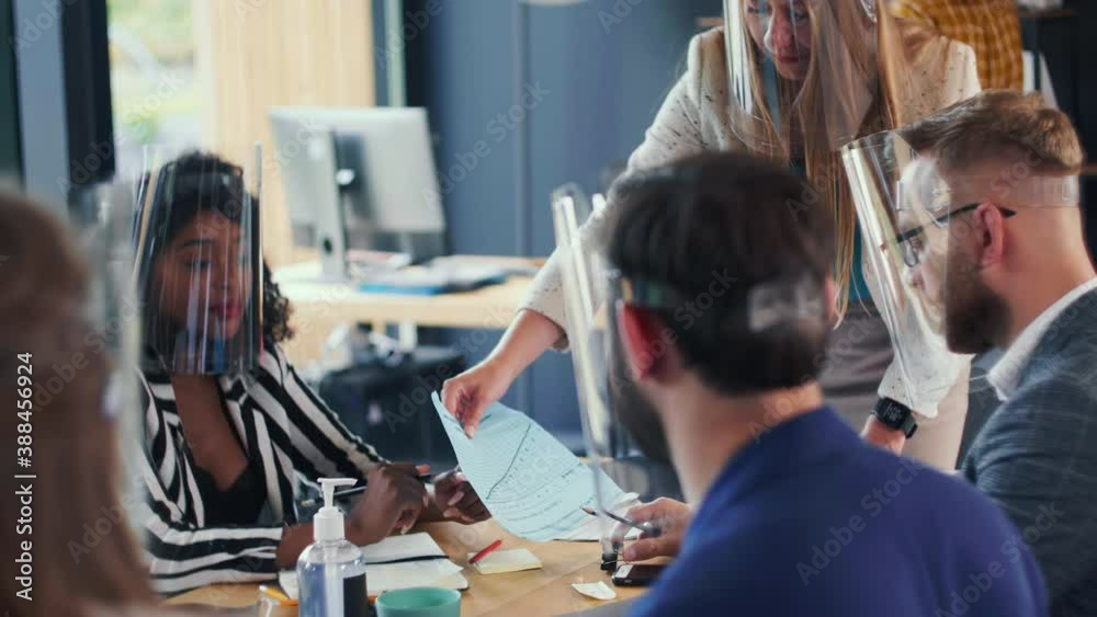 Beautiful Caucasian CEO business woman leads multiethnic team office meeting, all wearing coronavirus face shields. Beautiful Caucasian CEO business woman leads multiethnic team office meeting, all wearing coronavirus face shields.