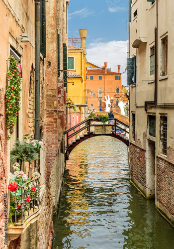 Venezia, Venice, Italy  July 24 2017 Tributary canal in Venice with an arched predestrian footbridge looking towards the helping hands photo