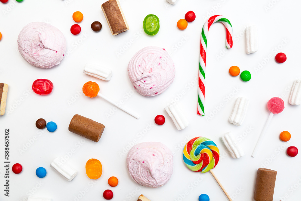 Many different sweets on a white background. Multicolored lollipops, caramel, candy canes, marshmallows, chocolate top view Many different sweets on a white background. Multicolored lollipops, caramel, candy canes, marshmallows, chocolate top view