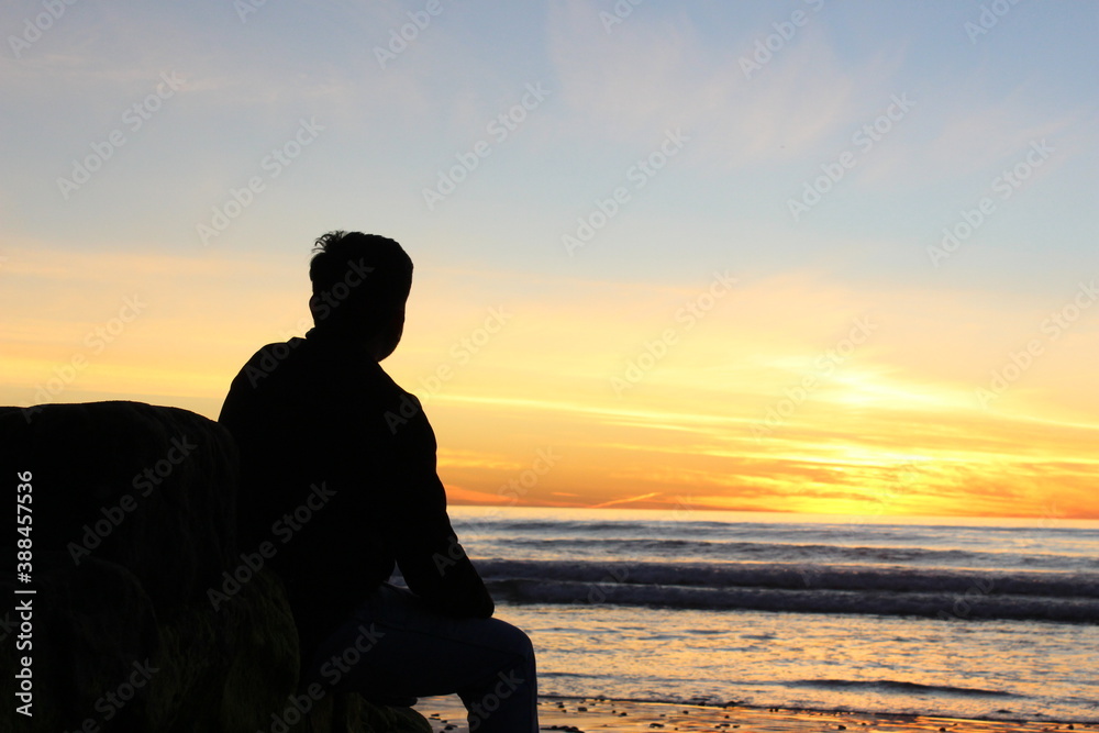 silhouette of a person sitting on the beach