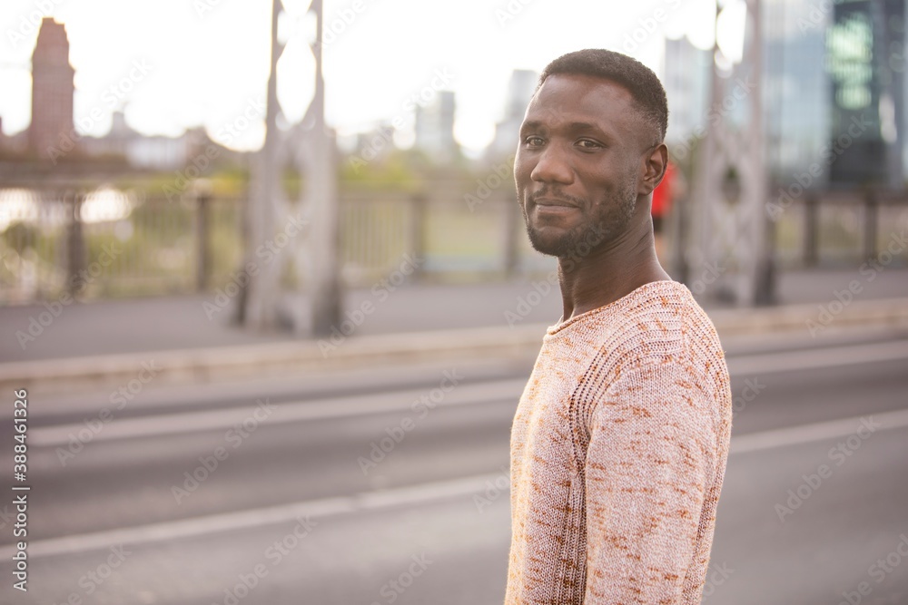Handsome Black Man in Sweater Posing on Street with Head Turned Handsome Black Man in Sweater Posing on Street with Head Turned