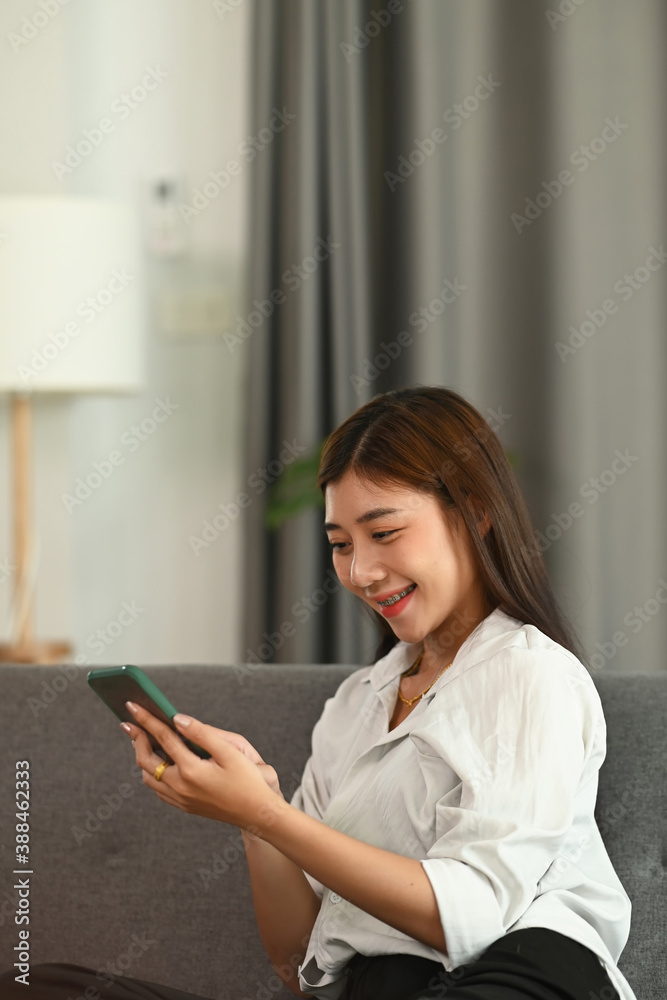 A young female reading social media news on smart phone mock up and sitting on sofa. A young female reading social media news on smart phone mock up and sitting on sofa.