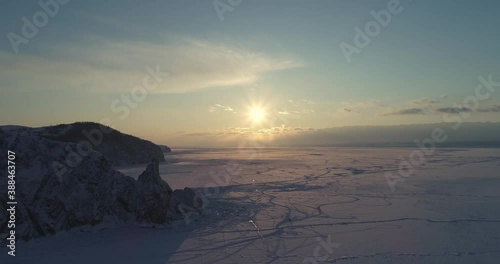 Aerial view of Shamanka rock and Cape Burkhan at sunset on frozen lake Baikal, Olkhon island in winter. Khuzhir, Siberia, Russia. Landscape of Russian natural landmark. 
