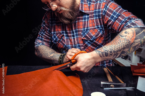 Artisan working with leather wording with leather goods in leather studio photo