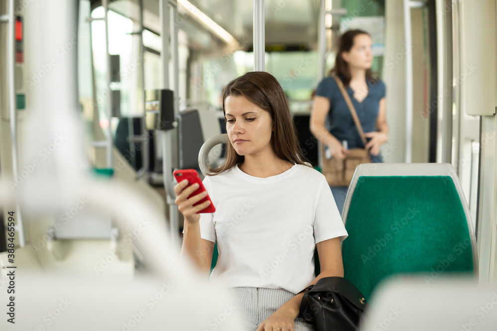 Fototapeta premium Woman using mobile phone in the cabin of a bus or tram. High quality photo