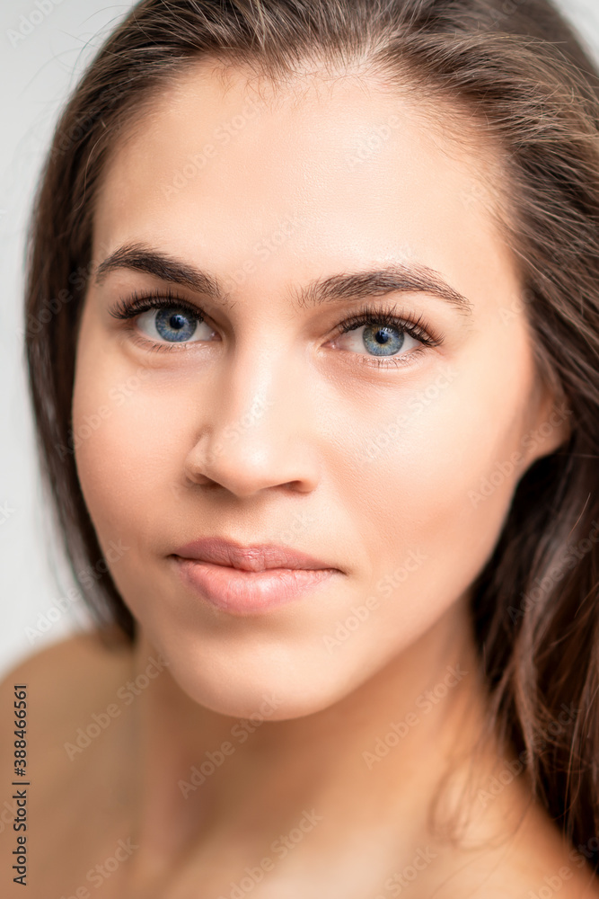Face portrait of young caucasian woman with natural make up and eyelash extensions looking at camera on white background Face portrait of young caucasian woman with natural make up and eyelash extensions looking at camera on white background