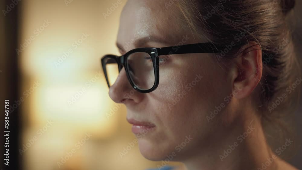 Woman in glasses looking on the monitor and surfing Internet. The monitor screen is reflected in the glasses. Work at night. Home Office. Remote work Woman in glasses looking on the monitor and surfing Internet. The monitor screen is reflected in the glasses. Work at night. Home Office. Remote work