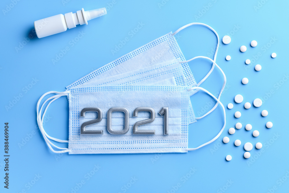 Three medical masks and numbers 2021, remedy for the common cold , lots of pills on a blue medical background. Concept of the protection against coronavirus, 2019-nCoV Three medical masks and numbers 2021, remedy for the common cold , lots of pills on a blue medical background. Concept of the protection against coronavirus, 2019-nCoV