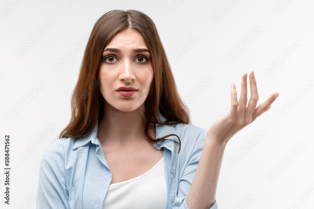 Portrait of confused girl pointing hand in sides. Studio shot, white background. Concept of doubt and uncertainty Portrait of confused girl pointing hand in sides. Studio shot, white background. Concept of doubt and uncertainty