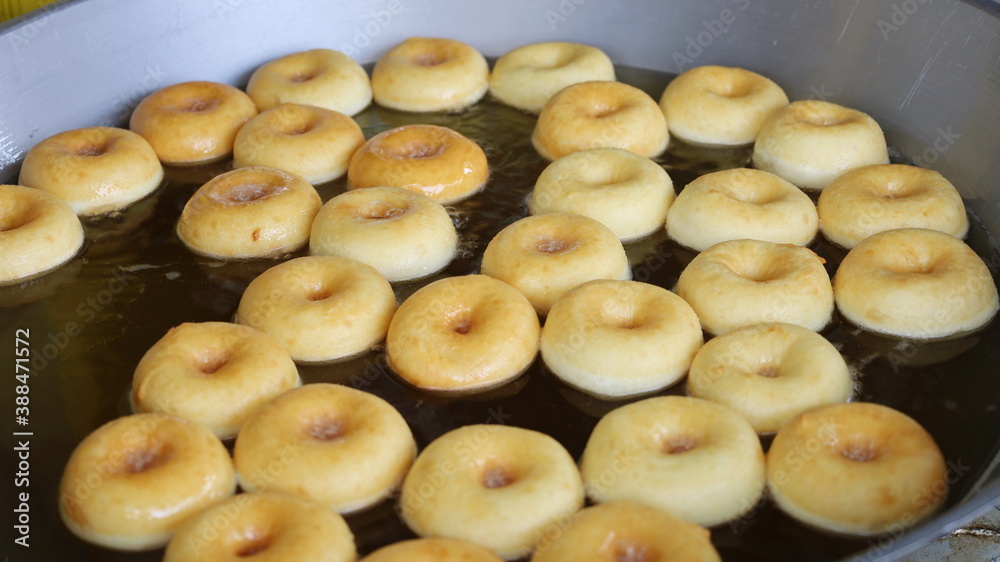 Donut snacks fried in hot oil. Process making doghnut or donuts, fried on frying pan. Long corridor. Selective focus