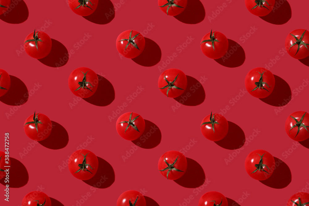 Cherry tomato pattern on a red background with hardlight. Flat lay, top view Cherry tomato pattern on a red background with hardlight. Flat lay, top view