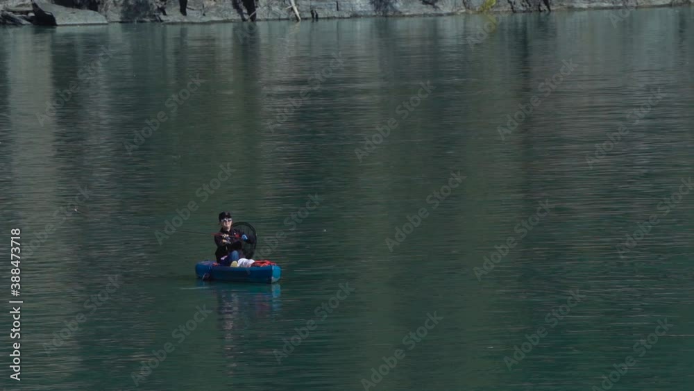 Slow motion fishing kayaker casting her rod and in the true nature of fishing a Coho salmon jumps in a different area than where she casted he lure. Slow motion fishing kayaker casting her rod and in the true nature of fishing a Coho salmon jumps in a different area than where she casted he lure.
