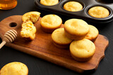 Homemade Cornbread Muffins on a rustic wooden board on a black background, side view. Close-up.