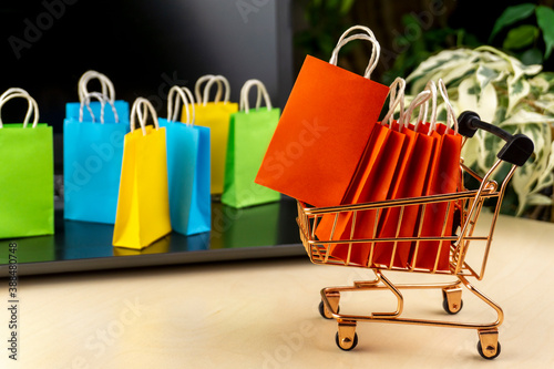 online shopping concept. little deliver boxes, smartphone, shopping bags, shopping bascket stand on laptop. copy space