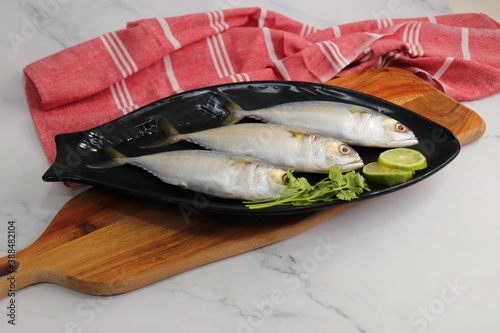 Uncooked Indian mackerel fish Rastrelliger kanagurta. also known as Bangda fish. Free copy space. Lemon wedge and coriander. top view fish background. online fish marketing.  photo