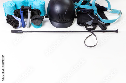 Flat lay of equestrian gear: helmet, brushes, whip, bandages, pads, dressage, bridle. Accessories and equipment for horse care and riding on the white background with copy space for yout text