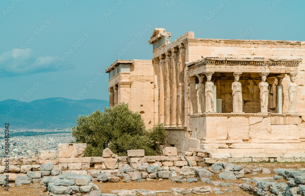 Caryatides, Erechtheion Temple at the Acropolis of Athens with a city view of Athens, Greece in the background