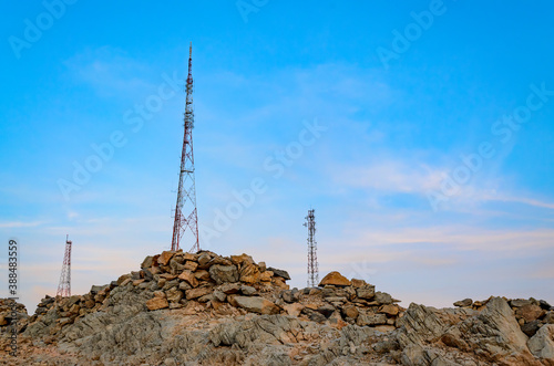 Three mobile towers on rocky mountains jutting out to the blue sky. From Muscat, Oman.