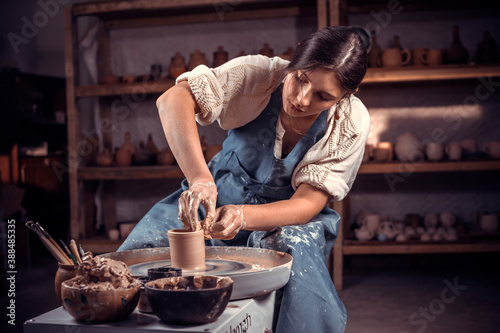 Beautiful pottery master is working on pottery wheel. Pottery workshop. photo