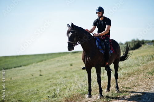 Arab tall beard man wear in black helmet, ride arabian horse. © AS Photo Family