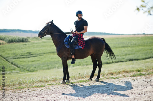 Arab tall beard man wear in black helmet  ride arabian horse.