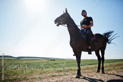 Arab tall beard man wear in black helmet, ride arabian horse. © AS Photo Family