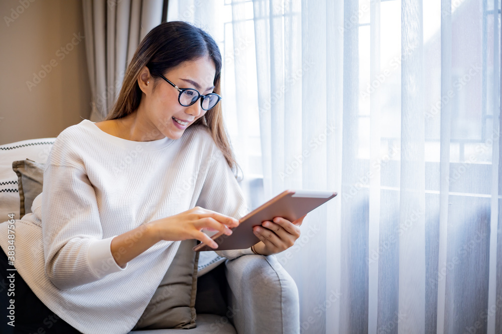 Asian woman who wear glasses relaxing on sofa while use tablet. Asian woman who wear glasses relaxing on sofa while use tablet.