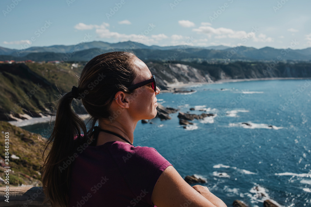 White woman looking to the ocean from a cliff, enjoying the views o the Cantabrian Sea, Spain.