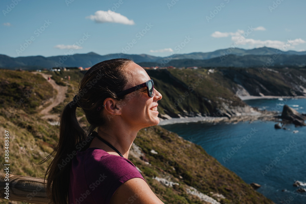 White woman enjoying the sun and the views in the Cantabrian Sea, in Spain.