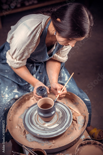 Charming young and cheerful woman molding a vase of clay on a potter's wheel. Concept of ceramic art. photo